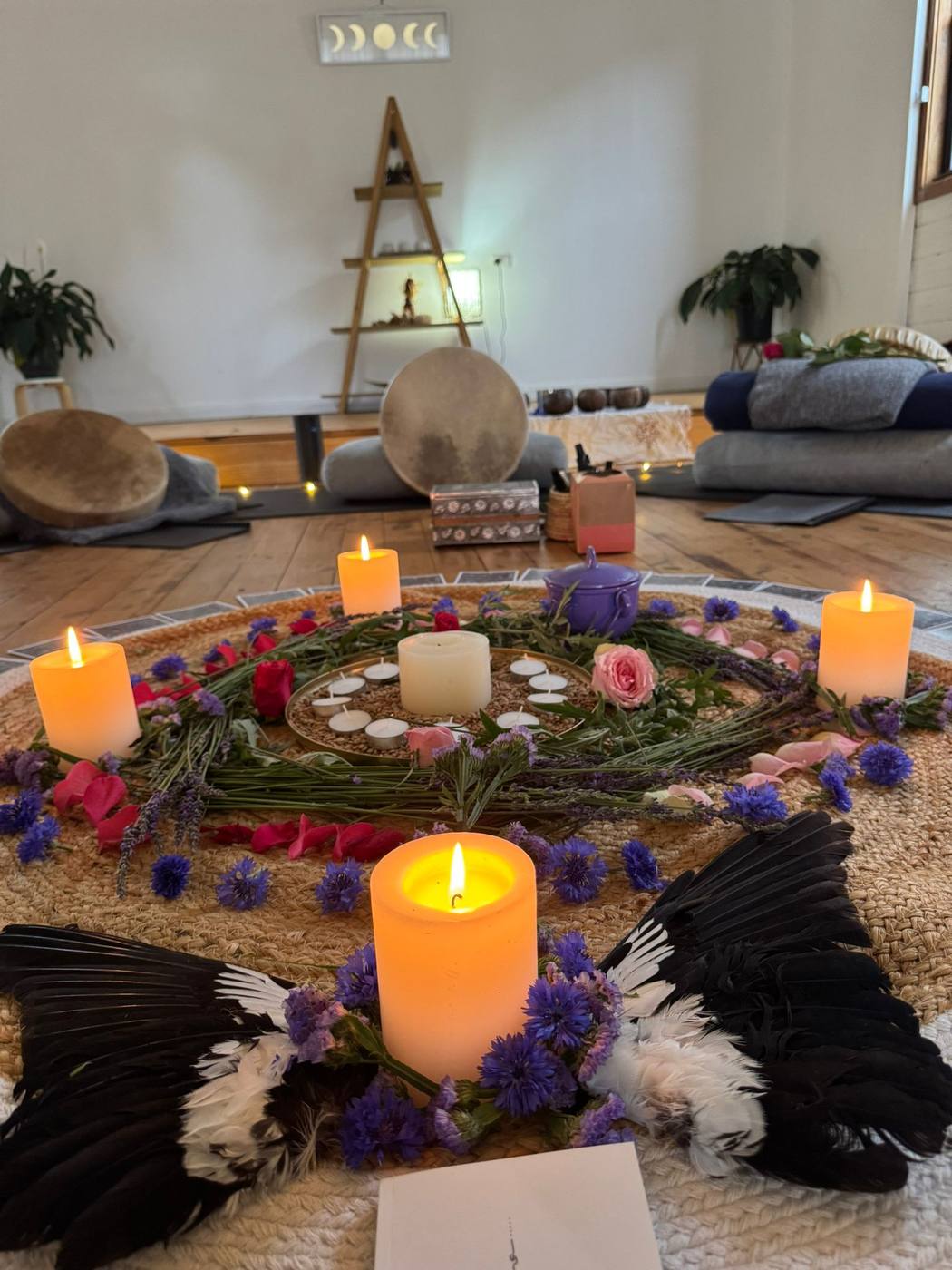 A candlelit ritual altar with flowers and feathers