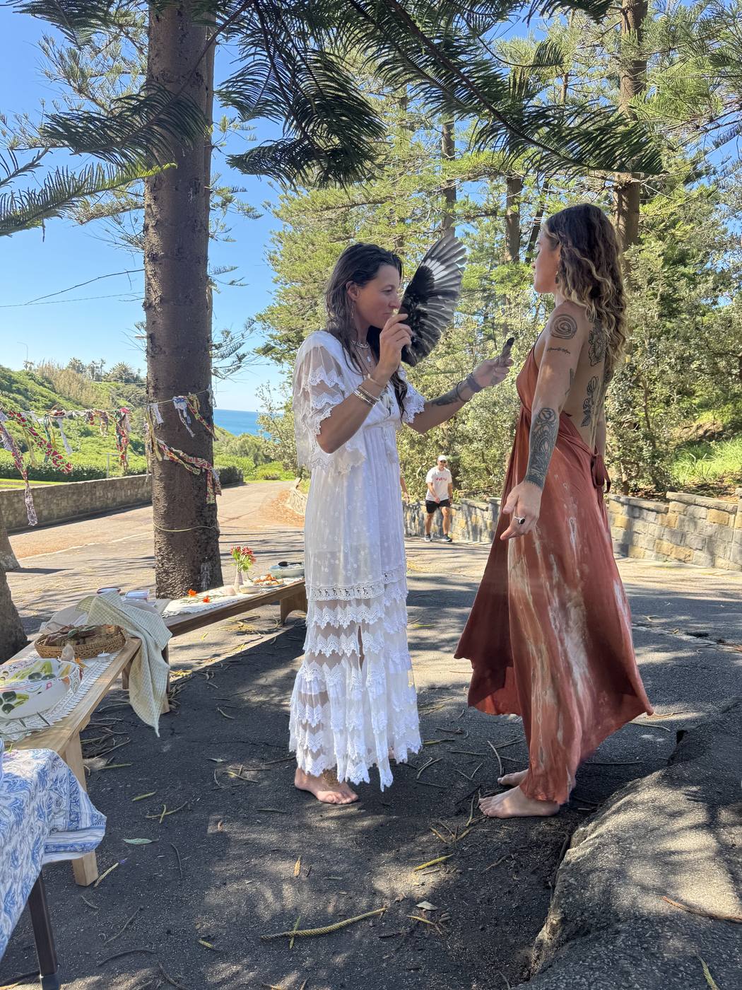 Ro sharing a ritual moment with a feather, overlooking the ocean